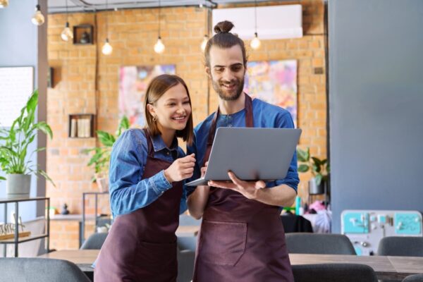 Business owner comparing seo pricing proposals on a laptop and paper documents