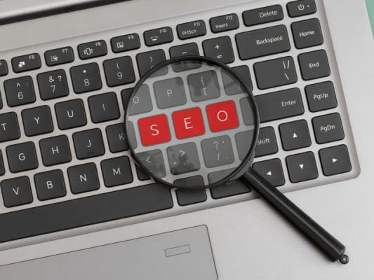 Seo-Fundamentals-On-Page-Off-Page-Technical-Seo Keyboard with a magnifying glass highlighting the word seo in red